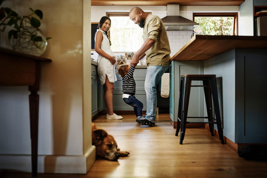 Happy family enjoying themselves in kitchen with dog laying down